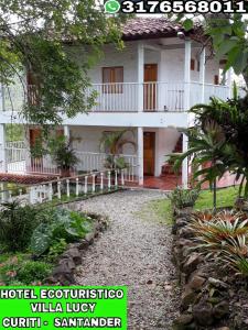 a large white building with a walkway in front of it at Hotel Ecoturistico Villa Lucy in Curití