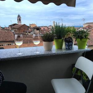 three glasses of wine sitting on a ledge with plants at Attico centro storico in Pavia
