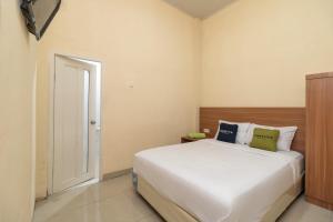 a bedroom with a large white bed with a wooden headboard at Urbanview Hotel Salsabilah Palembang by RedDoorz in Palembang +17 photos