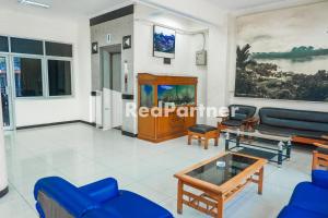 uma sala de estar com um sofá azul e uma mesa em Grand Kembar Hotel Mitra RedDoorz em Bandung