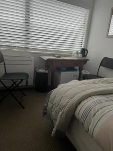 a bedroom with a bed and a desk and a window at TAURANGA, Bay of Plenty in Tauranga