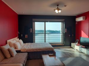 1 dormitorio con 2 camas, sofá y TV en Jeju Gaviota Pension, en Jeju