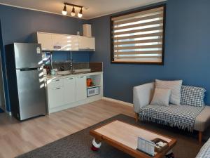 a kitchen with a refrigerator and a couch and a table at Jeju Gaviota Pension in Jeju