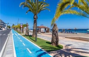une rangée de palmiers sur un trottoir à côté de la plage dans l'établissement Stunning Apartment In San Pedro Del Pinatar With Kitchen, à San Pedro del Pinatar