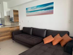 a living room with a brown couch with orange pillows at Suite de Lujo en Resort Playa Azul, Tonsupa in Tonsupa