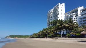 通苏帕Suite de Lujo en Resort Playa Azul, Tonsupa的享有棕榈树海滩和建筑的景色