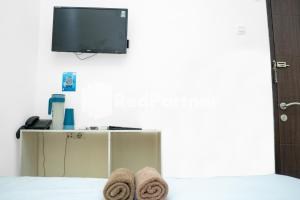 um quarto com televisão e toalhas numa cama em Jabrix Hotel Mitra RedDoorz em Bandung
