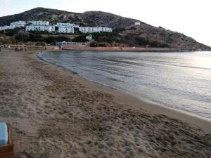 a sandy beach with houses on a hill next to the water at Anna's Apartment in Galissas