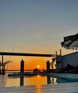 a swimming pool with a sunset in the background at Playa del Mar - Adults Only in Monopoli