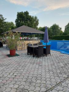 ギェネシュディアーシュにあるTulipan Bungalow Camping Resortのパティオ(テーブル、プールサイドのパラソル付)