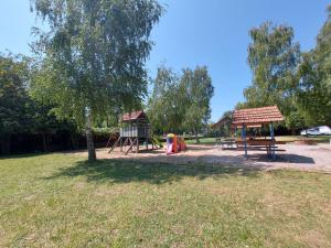 un parque con un parque infantil con un árbol y un columpio en Tulipan Bungalow Camping Resort, en Gyenesdiás