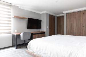 Dormitorio con cama, escritorio y TV en Capitalia - Apartments - Polanco - Julio Verne en Ciudad de México