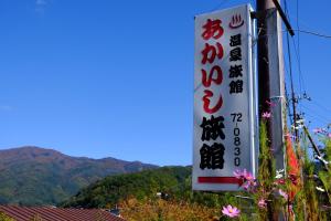 a sign for a restaurant with mountains in the background at Akaishi Ryokan in Fujikawaguchiko