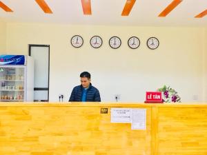 a man sitting at a counter in a store with clocks at Khách Sạn - Nhà Hàng So Oanh - Gần Thác Bản Giốc in Cao Bằng