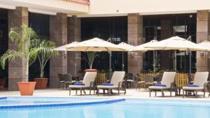 a pool with chairs and umbrellas next to a building at Amazing Junior Suite Space Available in Accra