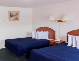 a hotel room with two beds with blue sheets at Prince Motel in Prince George
