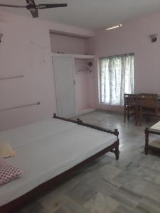 an empty room with a bed and a table at Hotel Peacock in Kovalam