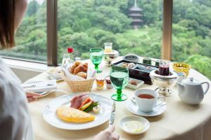 una mujer sentada en una mesa con comida y café en Hotel Chinzanso Tokyo, en Tokio