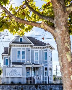 a blue house with a white fence and a tree at Rio Vista Inn & Suites Santa Cruz in Santa Cruz