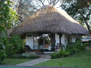 Cabaña pequeña con techo de paja y banco en Caprivi River Lodge, en Katima Mulilo