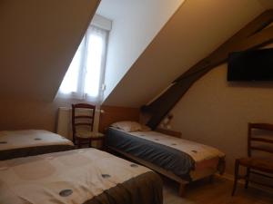 a attic room with two beds and a window at Le Lion D'or in Ouroux en Morvan