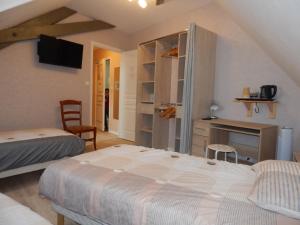 a bedroom with two beds and a desk and a tv at Le Lion D'or in Ouroux