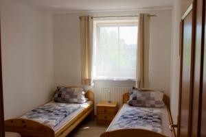 two beds in a small room with a window at Ferienwohnungen Seebauer in Nittenau