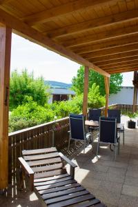 a patio with chairs and a table and a wooden roof at Ferienwohnungen Seebauer in Nittenau