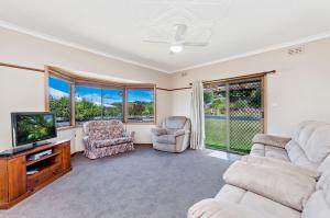 a living room with a tv and chairs and windows at Kepal House in Port Fairy