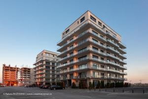 Un edificio alto de apartamentos en un estacionamiento. en De Silva, en Mamaia
