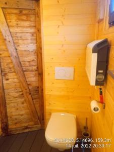 a bathroom with a toilet in a wooden wall at Cabane de l'Ermitage in Lessive