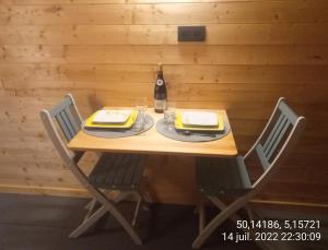 Cabane de l'Ermitage في Lessive: طاولة خشبية مع كراسي وزجاجة من النبيذ