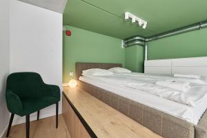 1 dormitorio verde con 1 cama y 1 silla verde en Mezzanine Studio Apartments Zarembowicza Wrocław Airport by Renters en Breslavia