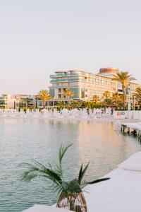 a pond with a palm tree in front of a building at Ilica Hotel Spa & Wellness Resort in Cesme