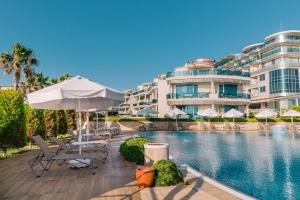 a resort with a swimming pool with chairs and an umbrella at Ilica Hotel Spa & Wellness Resort in Çeşme