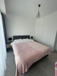 1 dormitorio con 1 cama grande con manta rosa en Apartaments Aphrodite, en Ghaziveran