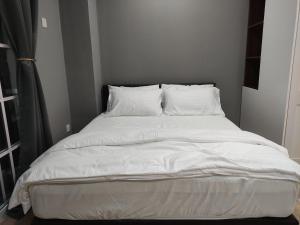 ein großes Bett mit weißer Bettwäsche und Kissen in der Unterkunft Kampar Bonvoy Champs Elysees 4pax Homestay in Kampar