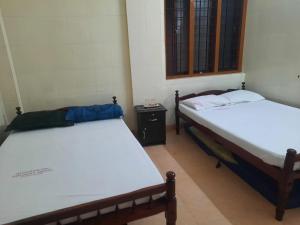 - 2 lits jumeaux dans une chambre avec une table dans l'établissement Devanjana Inn Guruvayoor, à Guruvāyūr