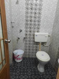 a small bathroom with a toilet and a bucket at Devanjana Inn Guruvayoor in Guruvāyūr