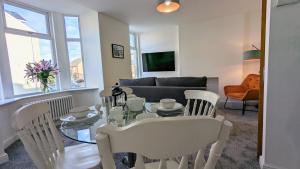 a living room with a glass table and white chairs at Ocean Pearl Apartment by Seaside Llandudno in Llandudno