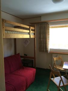 a bedroom with a bunk bed and a red couch at Appartamento Alpe di Siusi in Alpe di Siusi