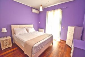 a purple bedroom with a bed and a window at Villa Mariah on the hill with seaview in Alepou
