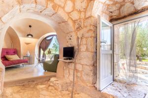 - un salon avec un mur en pierre et une fenêtre dans l'établissement Trulli Colle Specchia Intera Villa, à Cisternino