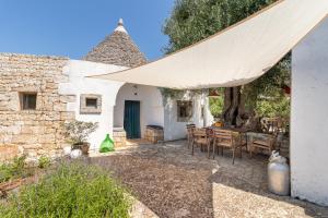 - une terrasse avec une table et un grand parasol dans l'établissement Trulli Colle Specchia Intera Villa, à Cisternino