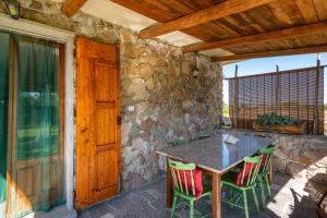 patio ze stołem i krzesłami oraz kamienną ścianą w obiekcie Villetta immersa nella Natura w mieście Calasetta