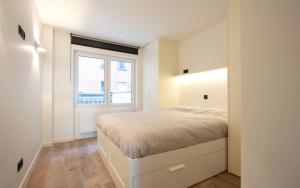 ein weißes Schlafzimmer mit einem Bett und einem Fenster in der Unterkunft Riva Bella 1.01 in Nieuwpoort