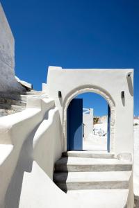a white building with a blue door and stairs at Acave Santorini Suites in Vóthon