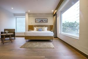a bedroom with a bed and a large window at The Sulit Whitefield in Bengaluru