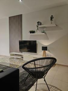 sala de estar con TV y silla en Qawra Apartment, en St Paul's Bay