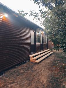 eine Holzhütte mit einer Bank davor in der Unterkunft Căsuța din livadă in 2 Mai